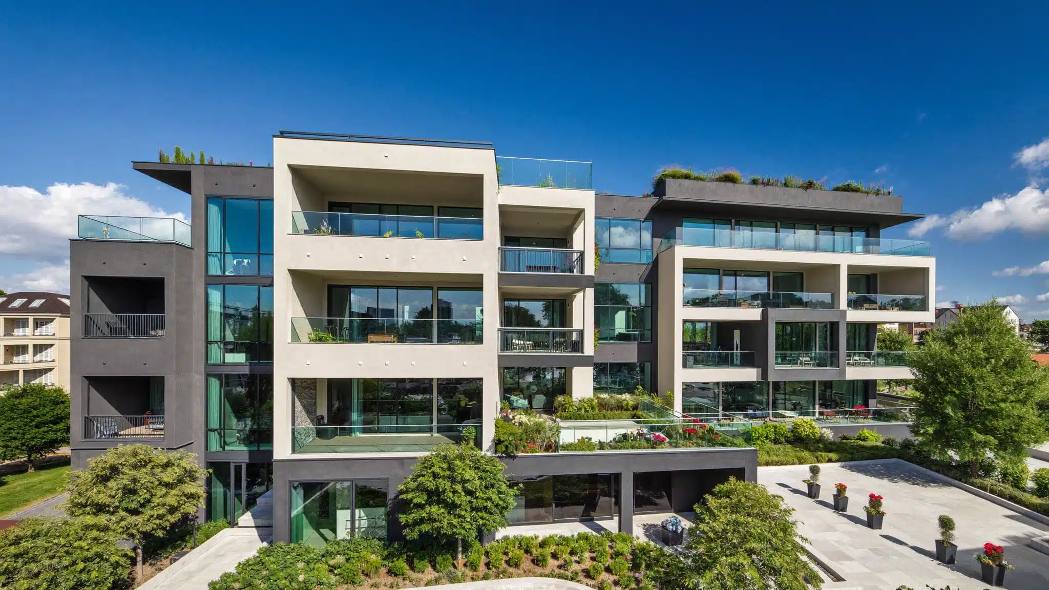 A modern high-rise condominium building featuring glass balconies and shared urban common areas.