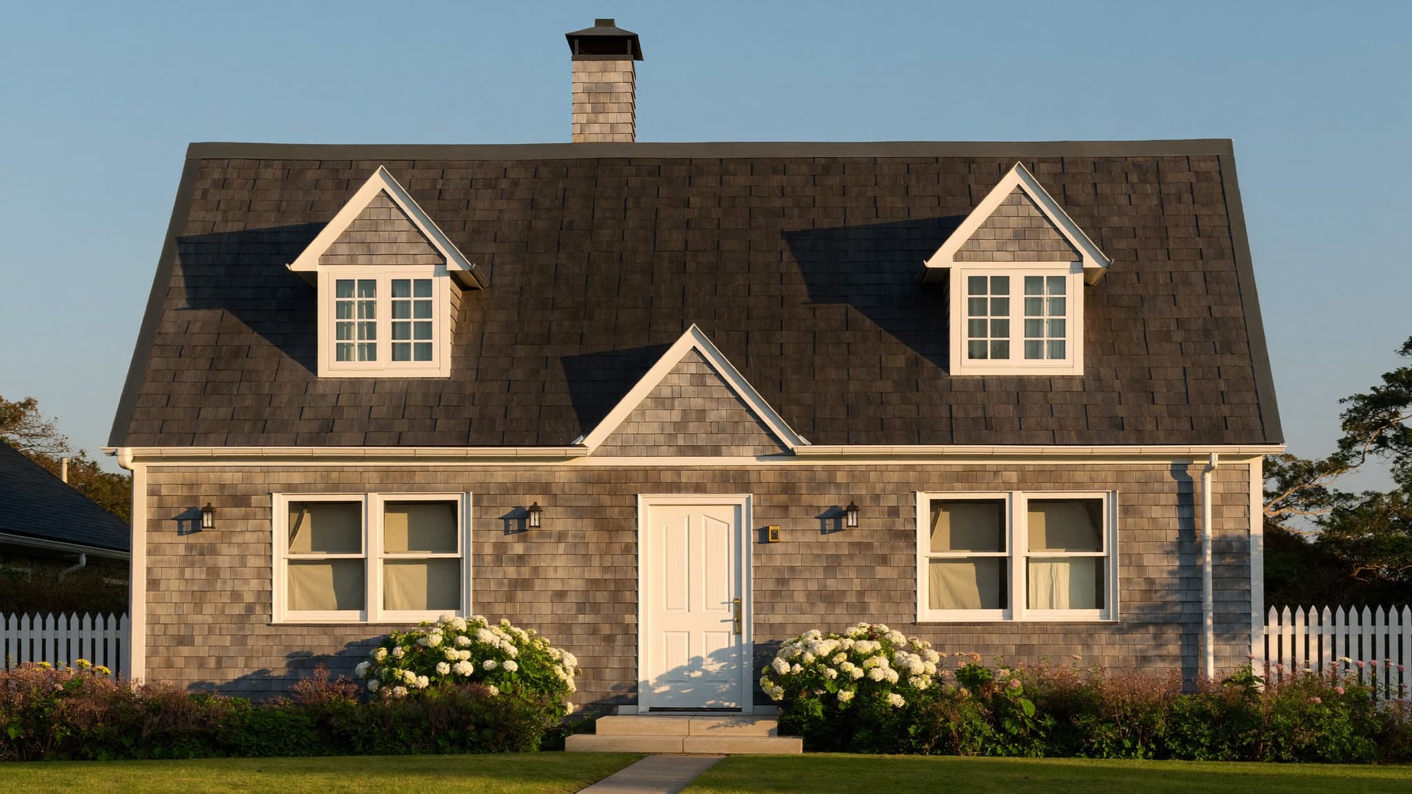 A traditional Cape Cod cottage with a steep gabled roof and symmetrical dormer windows.