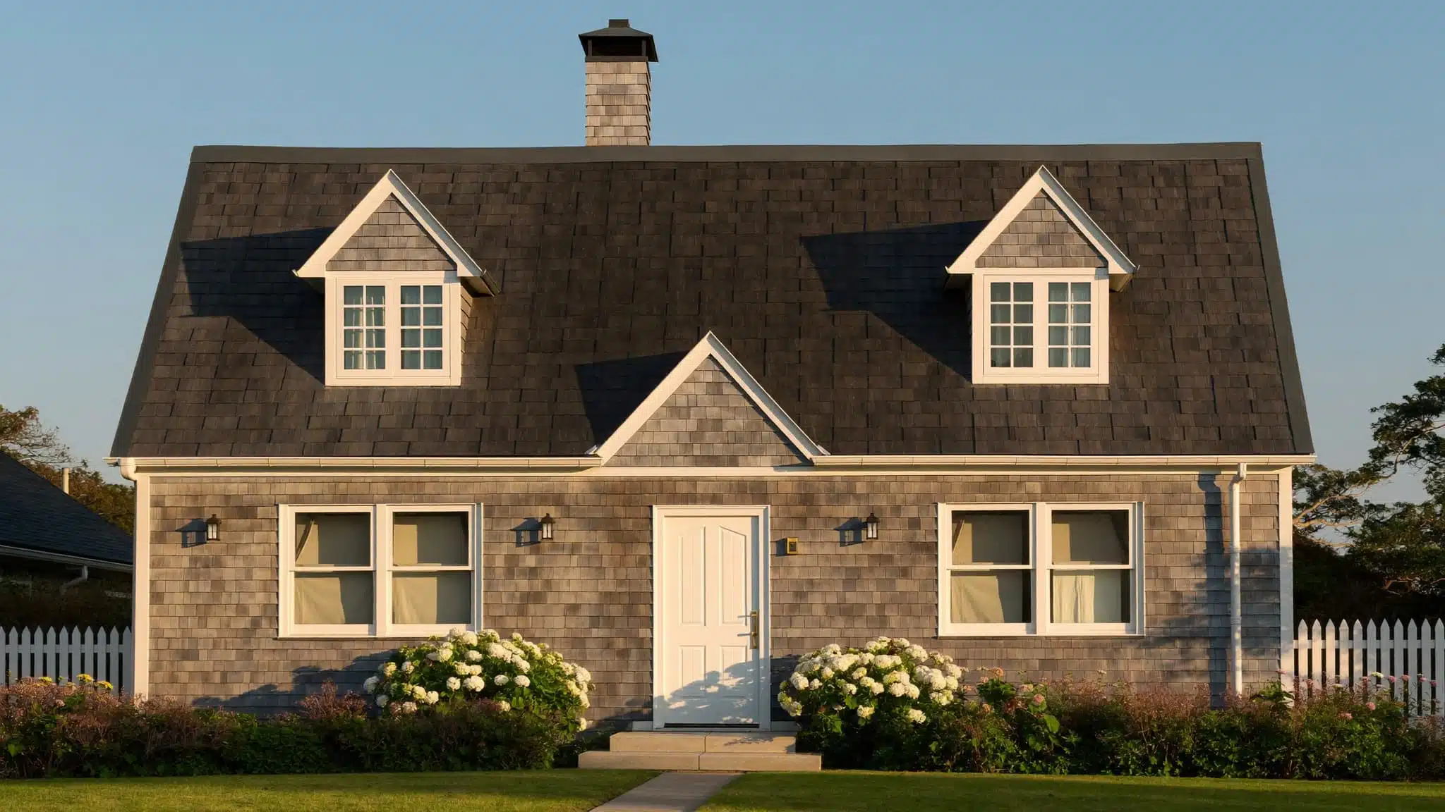 A traditional Cape Cod cottage with a steep gabled roof and symmetrical dormer windows.