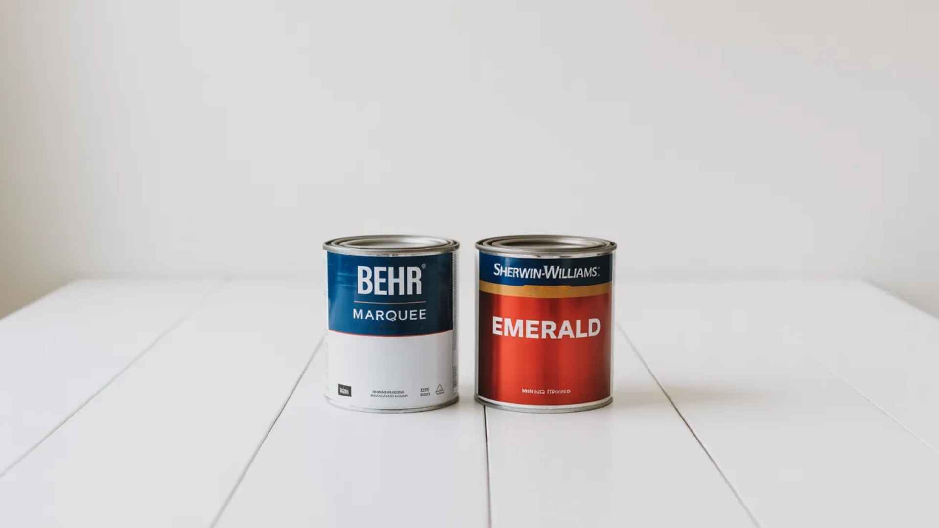 Behr Marquee and Sherwin-Williams Emerald paint cans displayed side by side for a paint brand comparison.