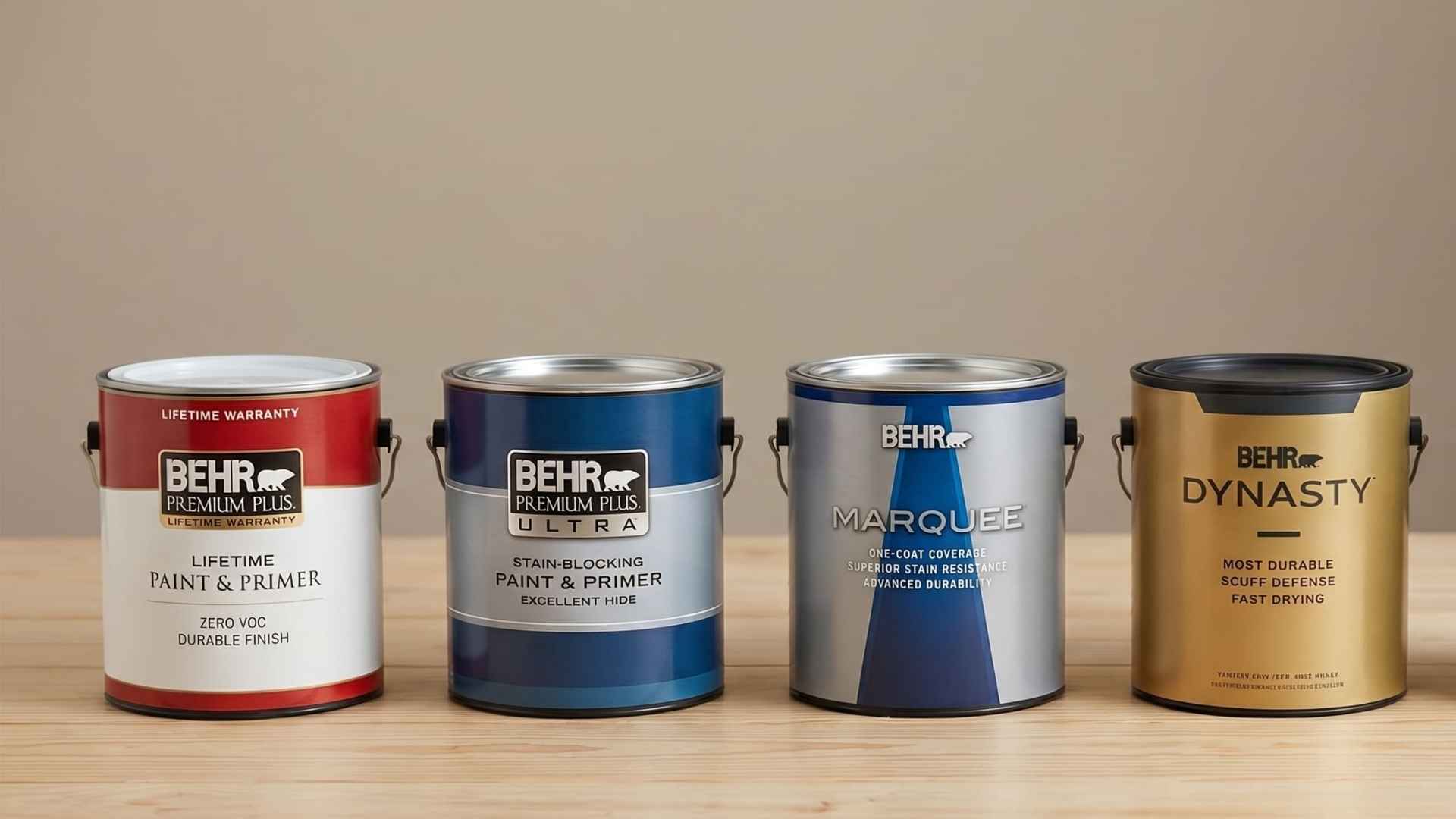 Four Behr paint cans displayed side by side on a wooden surface, comparing different paint product lines and finishes.