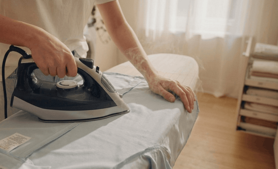 Person ironing polyester shirt inside out on low heat to protect outer surface from shine marks and heat damage