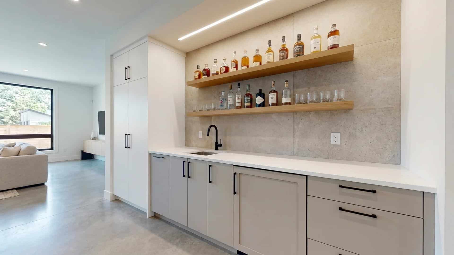 Modern minimalist wet bar with floating wood shelves and sleek neutral cabinetry.