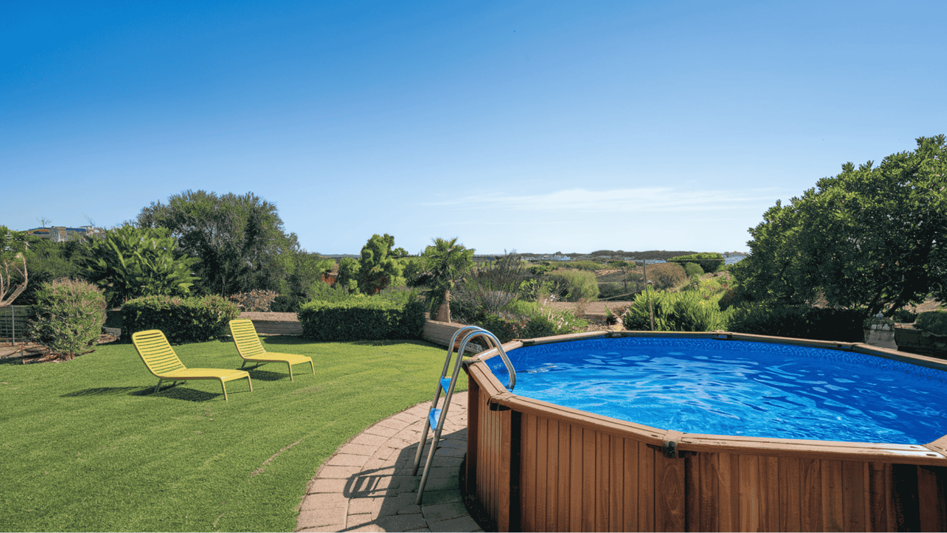 Round above-ground swimming pool with faux-wood siding panels on a green grass lawn.