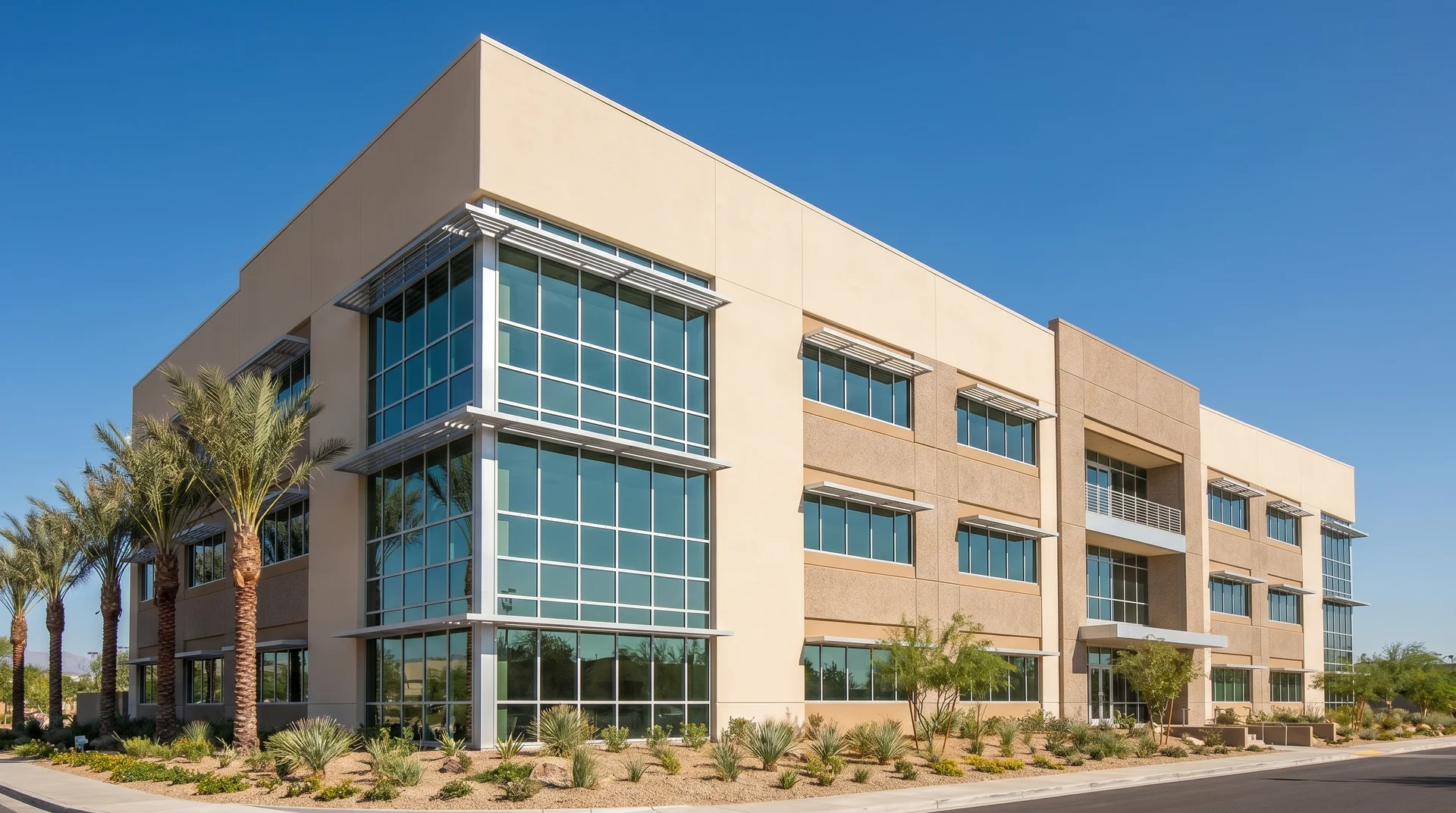 Modern commercial building with a clean, light tan stucco finish and architectural glass panels.