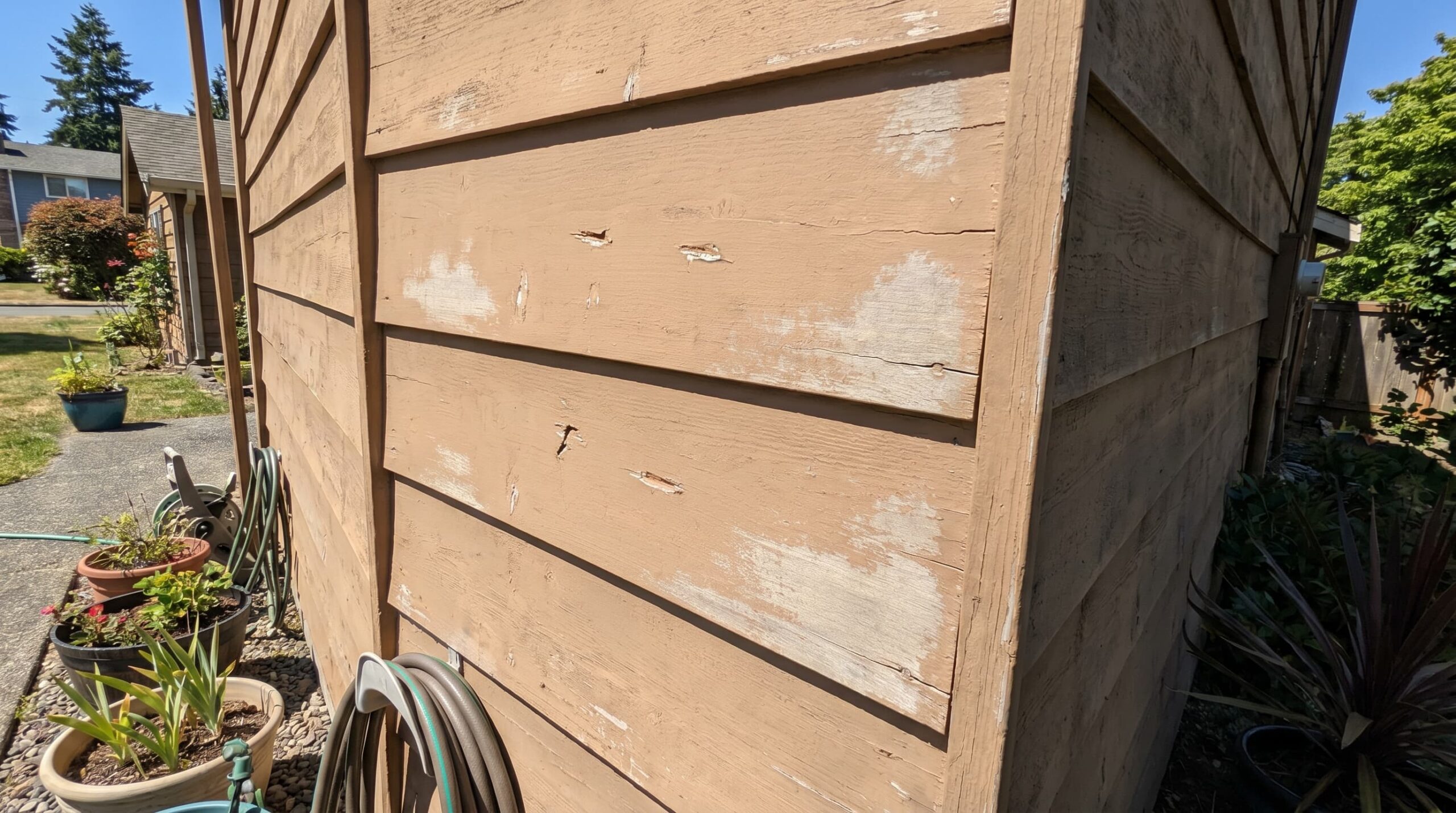 An image showing minor cosmetic damage on wood siding, including small scratches, dents, and fading, with areas of good condition visible alongside the damage