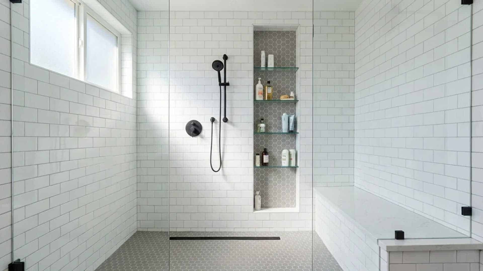 Bright walk-in shower with white subway tile walls, black handheld shower fixture, built-in storage niche, and a glass enclosure.