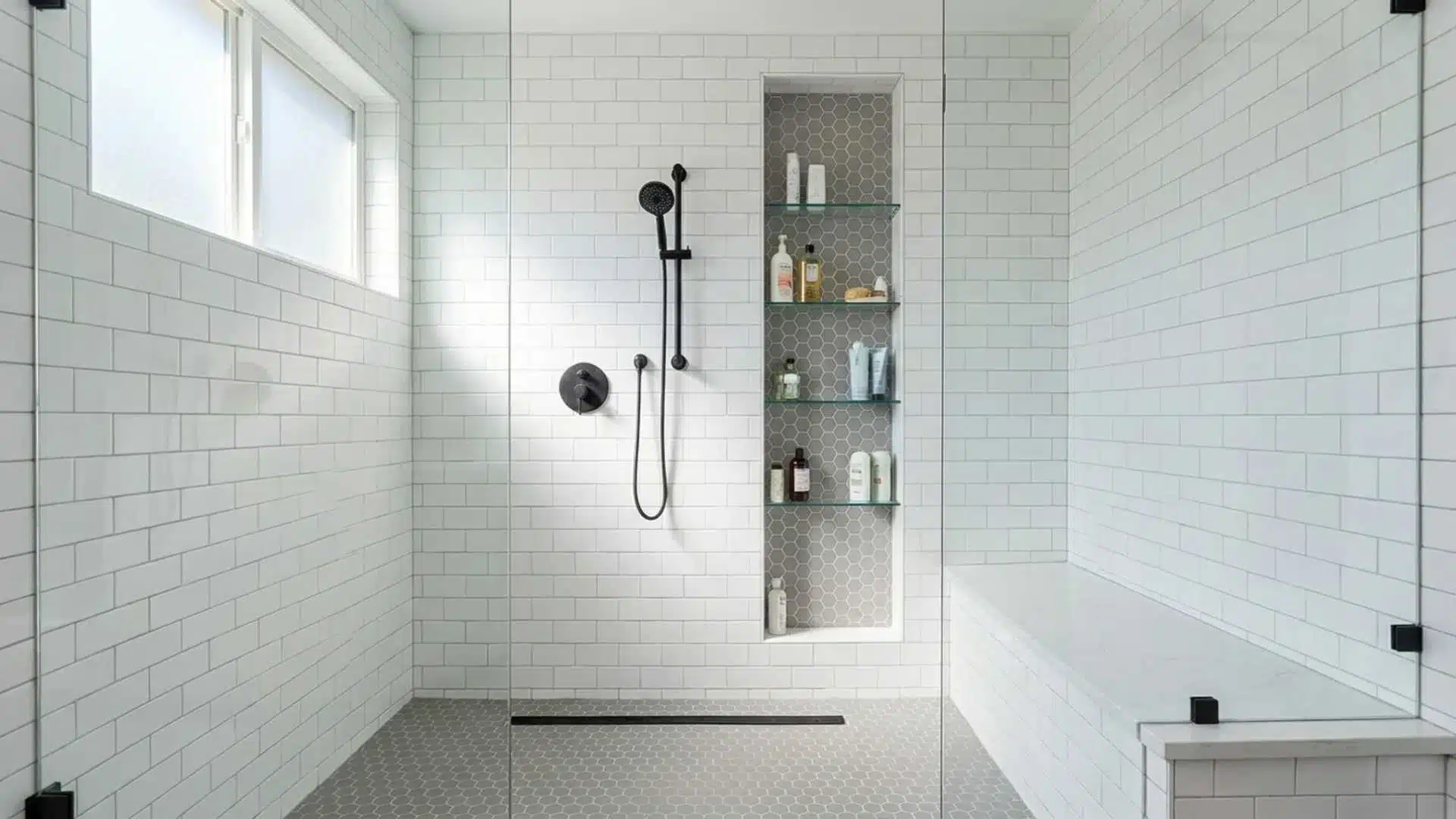 Bright walk-in shower with white subway tile walls, black handheld shower fixture, built-in storage niche, and a glass enclosure.