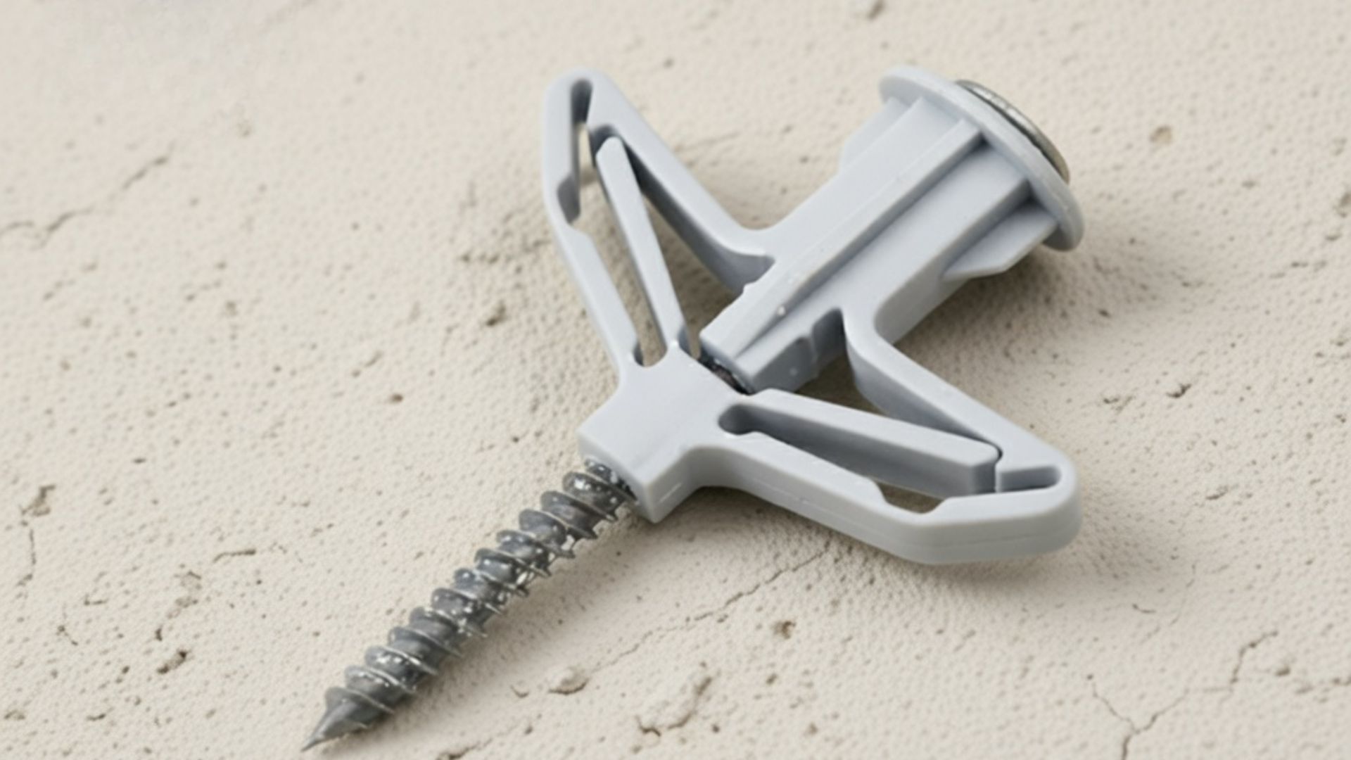 Winged plastic drywall anchor with expanding arms and screw, designed to grip securely behind drywall surfaces.