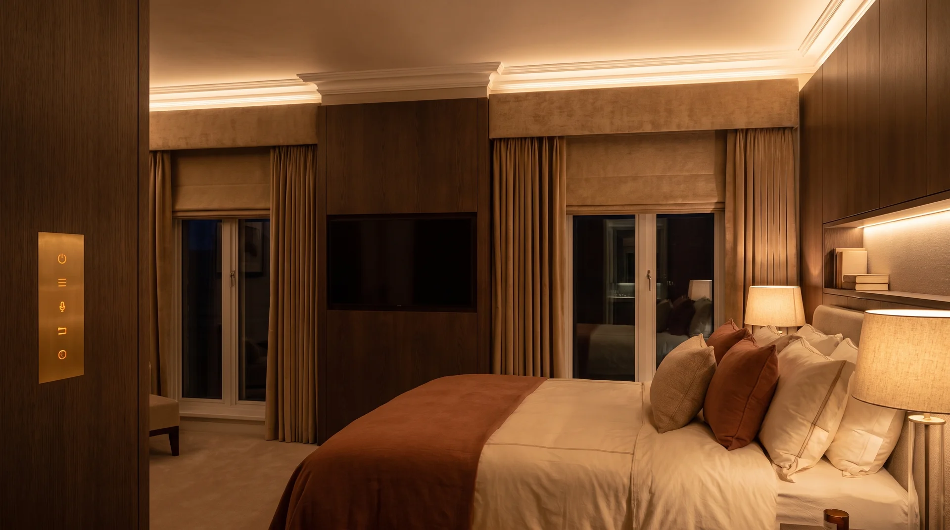 Luxury bedroom with fully invisible smart technology including concealed television behind wall panel, flush brass touch control and motorized blind pelmet.