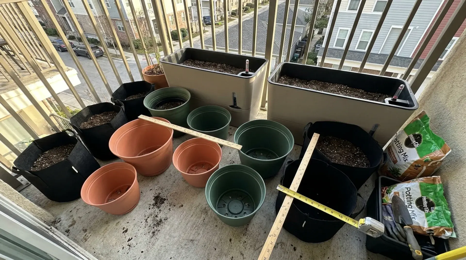 Apartment garden containers including plastic pots, fabric grow bags, and self-watering planters.
