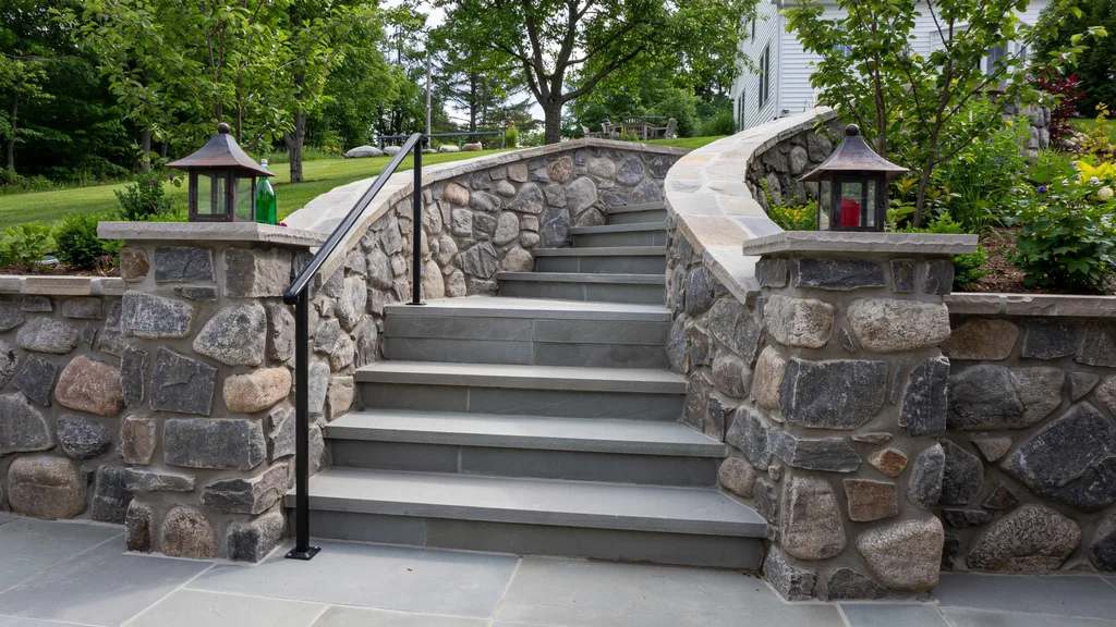 Dry stacked stone retaining wall on a landscaped garden slope showing natural stone construction without mortar for a durable low-cost solution