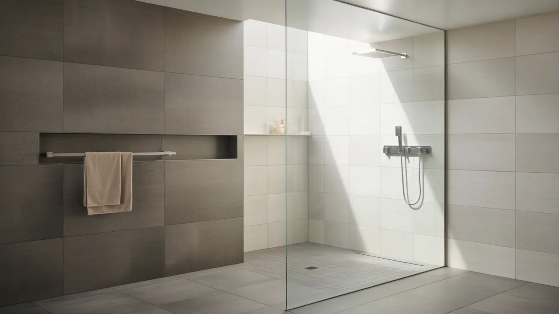 Modern minimalist wet room with gray tile walls, a clear glass partition, a wall-mounted shower fixture, and a towel rack.