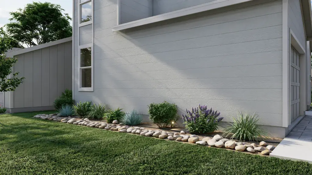 Foundation rock strip along house base improving drainage and keeping siding clean in front yard.