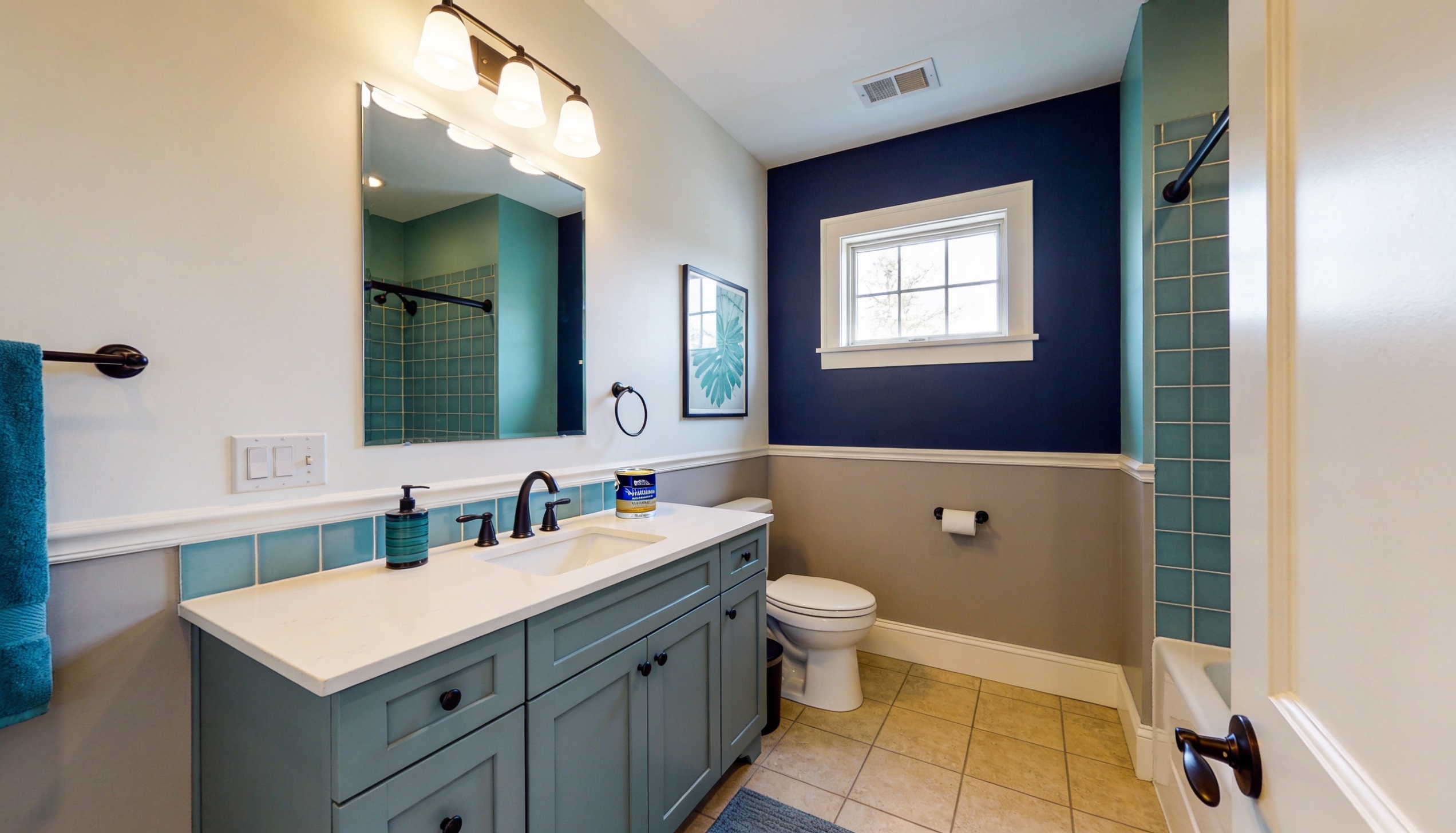 Bathroom with Sherwin-Williams colors, featuring teal and navy walls, contrasting with a soft beige lower half, and dark fixtures for a vibrant yet balanced design.